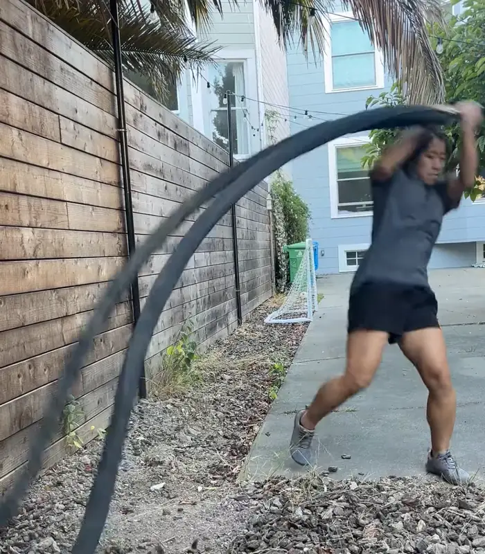 Selena Seto swinging a battle rope with overhead slams outdoors