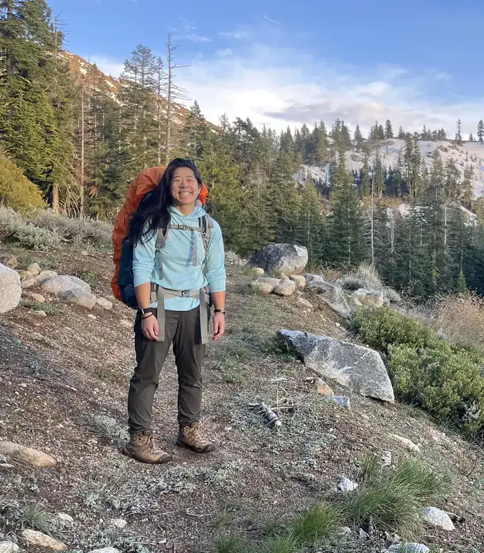 Selena Seto smiling with a backpack on a mountain trail